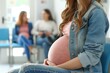 Close-up of an unrecognizable pregnant woman sitting in a waiting room indoors. Women's medical consultation