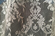 Detail of intricate patterns in an antique lace curtain hanging in a window