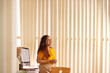 © IndiaPix - Portrait of a smiling businesswoman standing at desk and looking away in modern office