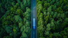 Aerial View Of A Blue Transportation Truck On An Empty Road In Middle Of A Green Trees Forest