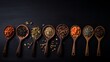 Various kinds of tea in wooden spoons on black table