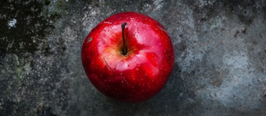 Wall Mural - Vibrant red apple on textured cement surface, fresh and natural conceptual image