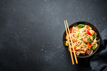 Poster - Asian noodles with chicken and vegetables at black background. Top view with space for design.