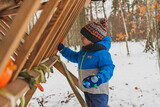 Fototapeta Niebo - child in winter forest feeding animals