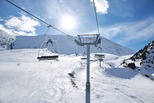 Chunkurchak Ski Resort In Kyrgyzstan. Active Recreation Skiing And Snowboarding. Empty Ski Lift Seats. Mountain Slope At Sunny Winter Day, Blue Sky.  Support Pillar, Cable Car Ride.