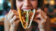 Closeup of a young woman smiling, opening her mouth to eat tacos that she is holding in her hands. Traditional Mexican or Spanish delicious food in a tortilla for a lunch meal in a restaurant