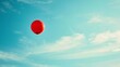 A red balloon flies in the sky