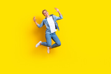 Wall Mural - Full length photo of lovely young lady jumping raise hands excited dressed stylish denim garment isolated on yellow color background