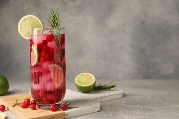 Wall Mural - Tasty cranberry cocktail with rosemary and lime in glass on gray textured table, space for text