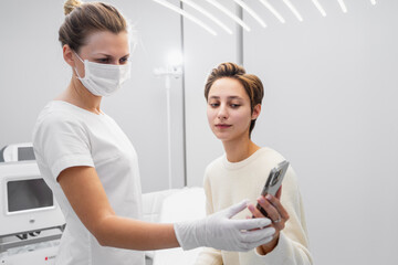 A young woman shows examples of the job she wants to get on her smartphone. Beauty salon.