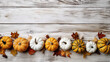 A group of pumpkins with dried autumn leaves and twigs, on a white color wood boards