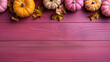 A group of pumpkins with dried autumn leaves and twigs, on a fuchsia color wood boards