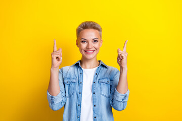 Wall Mural - Photo portrait of pretty young girl look point up empty space banner dressed stylish denim outfit isolated on yellow color background