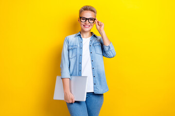 Wall Mural - Photo portrait of lovely young lady touch specs hold netbook dressed stylish denim garment isolated on yellow color background