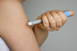 Blue self injection pen near female shoulder. Medicine and treatment concept