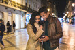 Happy multiracial couple sharing a moment with smartphone at night
