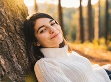 Latin Young Smiling Woman Lying On The Grass, Against Tree Trunk. Relaxation In Nature.