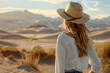 Girl with straw hat and white shirt, on her back in an arid desert