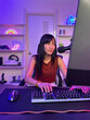 © DG PhotoStock - Happy Asian young woman sitting in front of the gaming computer in the room.