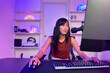 © DG PhotoStock - Happy Asian young woman sitting in front of the gaming computer in the room.