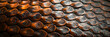 Close-up of metallic snake scales in orange hues with a dark background.