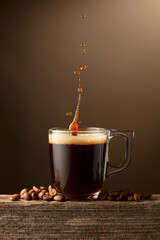 Wall Mural - Espresso coffee glass cup with splashes on a brown background.