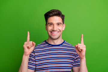 Poster - Photo of pleasant nice guy with stubble dressed striped t-shirt directing at proposition empty space isolated on green color background