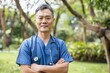 Portrait of a male Asian doctor wearing scrubs in a park