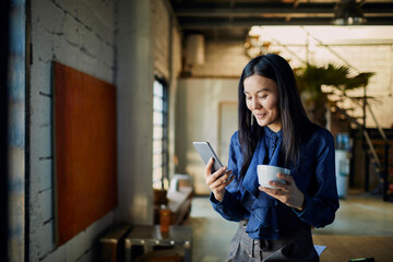 Wall Mural - Young business woman using smartphone on coffee break in modern workspace