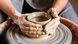 Potter's hands molding clay vase on a potter's wheel. Tactile process of pottery-making, ear