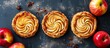 © TheWaterMeloonProjec - Three delicious apple pies, a classic dessert made with apples, are displayed on a table alongside fresh ingredients. This baked good is a popular sweet dish in many cuisines