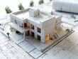 © Tuannasree - A detailed model of a modern house placed on architectural blueprints, illustrating the planning and design process in architecture.