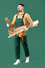 Canvas Print - Male carpenter with wooden planks on green background