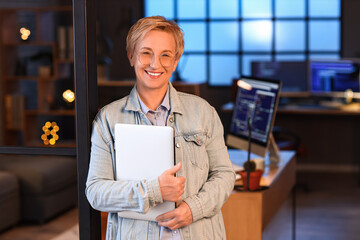 Poster - Mature female programmer with laptop in office at night