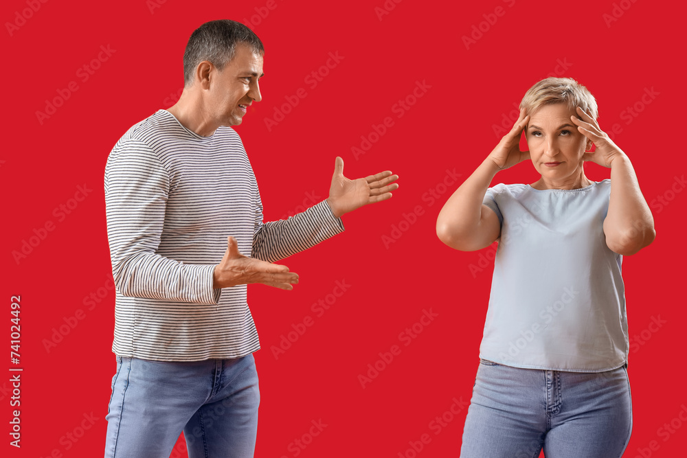 Mature couple quarreling on red background