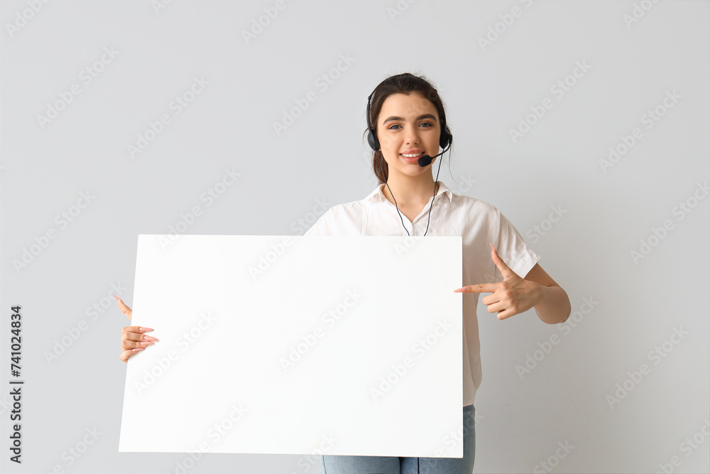 Female technical support agent with blank poster on light background