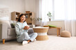 © Pixel-Shot - Beautiful young Asian woman in stylish hoodie with cup of tea sitting on floor at home