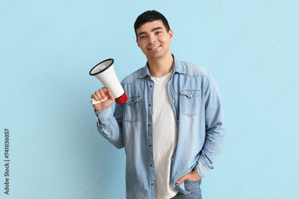 Happy young man with megaphone on blue background