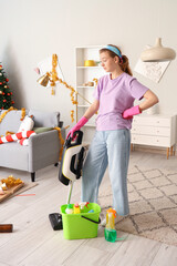 Poster - Female janitor with cleaning supplies in messy living room after New Year party