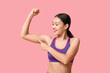 © Pixel-Shot - Young woman in sportswear showing muscles on pink background