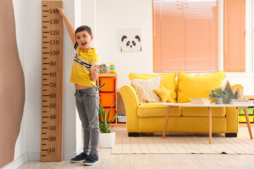 Sticker - Confused little boy measuring height near wooden stadiometer at home