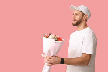 Canvas Print - Young delivery man with bouquet of beautiful tulips on pink background