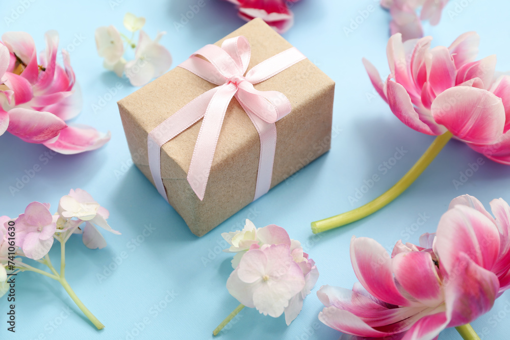 Composition with gift box and beautiful flowers on cyan background