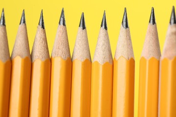 Wall Mural - Many sharp graphite pencils on yellow background, macro view