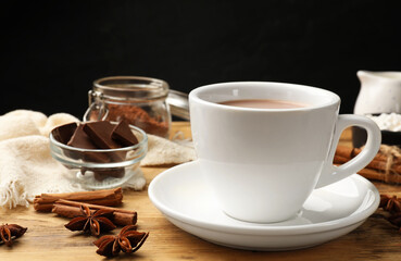 Poster - Tasty hot chocolate in cup and spices on wooden table, closeup