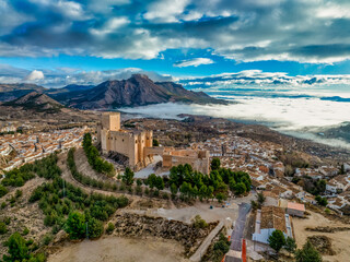 Aerial view of Velez Blanco hilltop medieval castle with square tower, restored Gothic palace above the town with dramatic sky