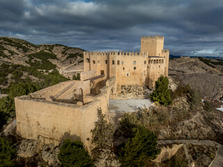 Canvas Print - Aerial view of  Velez Blanco castle on a hilltop and town with one or two floor houses whitewashed walls and tiled roofs with dramatic cloudy sky in Andalusia Spain