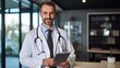 © liliyabatyrova - Portrait of a confident, happy male doctor standing with a tablet in a modern clinic. Profession Therapist, Pediatrician, Neurologist, Surgeon, Orthopedist, Science, Medical care concepts.
