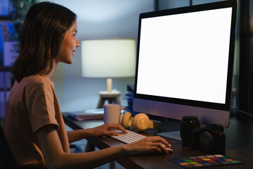 Young Asian woman sitting on chair and working at the computer with blank screen in home on the night.