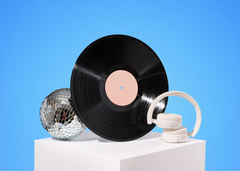 Disco and music idea. Vinyl record, disco ball and white wireless headphones.